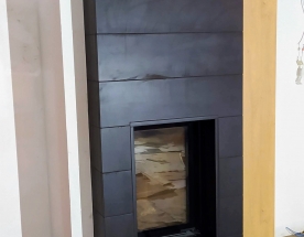 Nasze realizacje - Nowoczesne NR-N-259 - Nowoczesny pieco-kominek z wysokim wkładem marki Unico. Obudowa zbudowana rzemieślniczo tj. pustak z płytą krzemiano-wapienną, na froncie zastosowana płyta szamotowa. Do paleniska na wyjściu spalin podłączona masa akumulacyjna (krążki - ok 150kg) utrzymująca piec dłużej ciepły po wygaśnięciu. Wykończenie zewnętrz to czarne matowe kafle wielkogabarytowe. projekt: Marcin Deręgowski